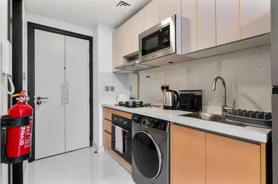 a kitchen with a washing machine and a sink at Chic Studio near Dubai Miracle Garden & Expo City in Dubai