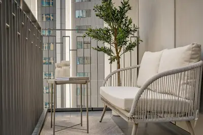 a chair and a plant in a room with a window at Daniels 2BR at Creek Gate with Canal View in Dubai