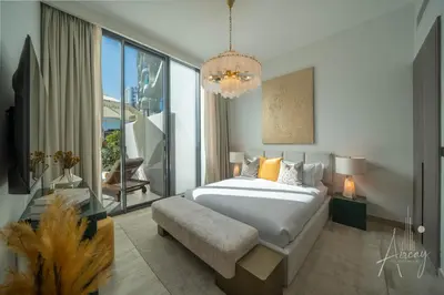 a bedroom with a large bed and a chandelier at 1BR Sunlit Modern Retreat with Private Sunbeds in Dubai