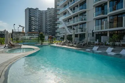 a large swimming pool with chairs and a building at 1BR Sunlit Modern Retreat with Private Sunbeds in Dubai