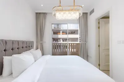 a bedroom with a large white bed and a chandelier at Contemporary 2BR in JVC With Pool, Gym & Relaxing Stay in Dubai
