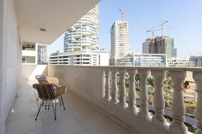 a balcony with a chair and a view of the city at Contemporary 2BR in JVC With Pool, Gym & Relaxing Stay in Dubai