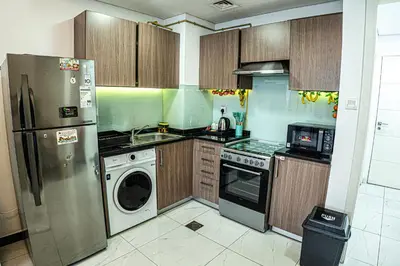 a kitchen with a refrigerator and a dishwasher at Crystal Residence-Modern Home Pool view Peaceful Next to Circle Mall in Dubai