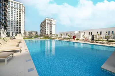 a large swimming pool with chairs and buildings at Mahogany 26 - 4BR 9PAX - Dubai Hills Park Peaceful in Dubai
