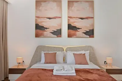 a bedroom with a large bed with two pictures on the wall at Luxury 1BR at Royal Regency, Refined City Living in Dubai