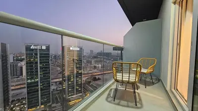 a balcony with two chairs and a view of a city at Bella-Rose-Fully Furnished Cozy High Floor Amazing View in Dubai