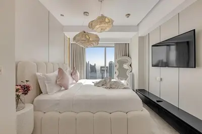a bedroom with a large white bed and a television at Waves - JW Marriot Residence Modern & Chic 1BR Apt in Dubai