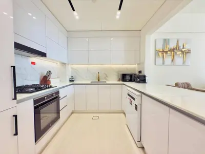 a white kitchen with white cabinets and appliances at Elegant and Stylish Retreat - Lavender Binghatti 1103 in Dubai