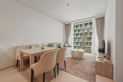 a dining room with a table and chairs and a couch at Luxury 2BR at Seven Palm Rooftop Pool&Beach Access in Dubai