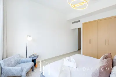 a bedroom with a white bed and two chairs at LUX The Armada Suite JLT in Dubai