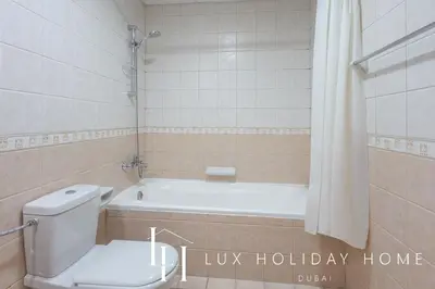 a bathroom with a toilet and a bath tub at LUX The Armada Suite JLT in Dubai