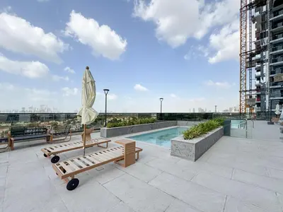 a patio with a pool and benches and a umbrella at Stylish 1 BR in Cloud Tower in Dubai