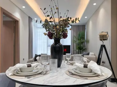 a table with plates and a vase with flowers on it at Stylish 1 BR in Cloud Tower in Dubai