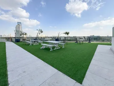 a group of picnic tables on a green field at Stylish 1 BR in Cloud Tower in Dubai