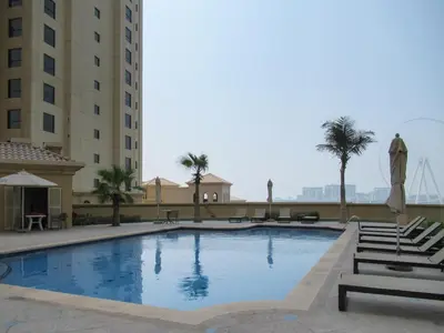 a large swimming pool with chairs and a building at Upgraded apartment just steps away from JBR beach in Dubai