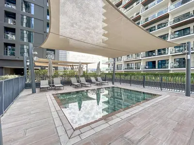 a swimming pool in a building with chairs and an umbrella at Central Modern Studio with Floor to Ceiling Windows in Dubai