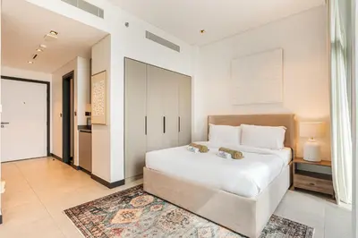 a bedroom with a large white bed and a rug at Central Modern Studio with Floor to Ceiling Windows in Dubai