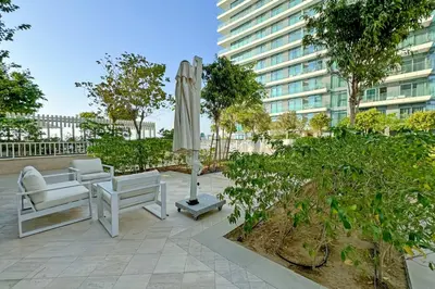 a patio with a white umbrella and chairs and a table at Miami Vibes - 1BR with Private Beach, Sea, Palm View in Dubai
