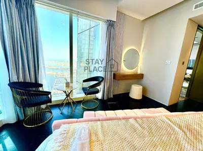 a bedroom with a bed and chairs and a large window at FENDI 2BR- 67 Floor Sea, Atlantis & Dubai Eye View in Dubai