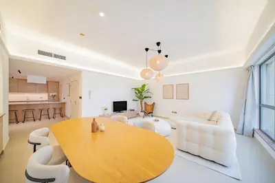 a living room with a wooden table and white furniture at Newly renovated, near the beach, with a Marina View in Dubai