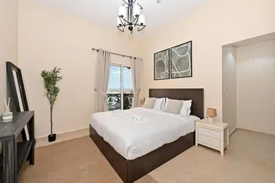 a bedroom with a bed and a desk and a window at Bloomfields Homey 1BR in Al Ramth 37 in Dubai