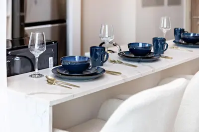 a table with plates and wine glasses on it at Wonderful 1BR Apartment at East Crest in Dubai