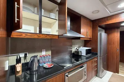 a kitchen with wooden cabinets and a black counter top at Burj Khalifa and Fountain View 3BR in Dubai