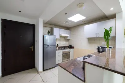a kitchen with a stainless steel refrigerator and white cabinets at 1Bedroom in Marina with Metro and Tram Access in Dubai