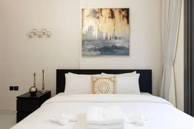 a bedroom with a large bed with white sheets at Stylish pool view 1BR in Barsha South sleeps 5 in Dubai