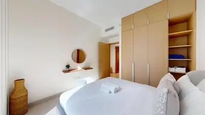 a white bedroom with a white bed and a mirror at Vacationer l Contemporary 2 Bedroom l Pool, Gym, Private Beach Access in Dubai