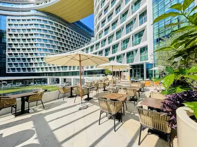 an outdoor patio with tables and chairs and buildings at Luxury studio with beach and pool access. in Dubai