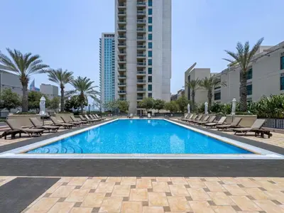 a swimming pool with lounge chairs and a building at Vacationer l Spacious Studio l Canal View l The Greens in Dubai
