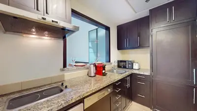a kitchen with brown cabinets and a sink and a window at Vacationer l Spacious Studio l Canal View l The Greens in Dubai