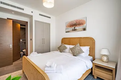 a bedroom with a large bed with white sheets at Modern 1BR with Guest Room l Sobha Hartland The Crest Tower C in Dubai
