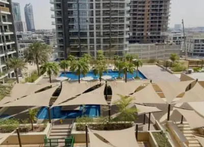 a pool with umbrellas and palm trees in a city at Luxury Living in JVC 1BR Apartment in Dubai