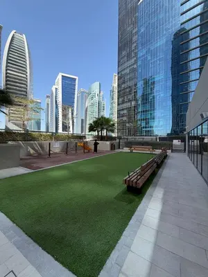 a park with benches and green grass in a city at Zada Tower 1 Bedroom Apartment in Business Bay in Dubai
