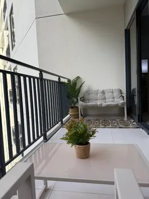 a white couch sitting on a balcony with plants at Zada Tower 1 Bedroom Apartment in Business Bay in Dubai