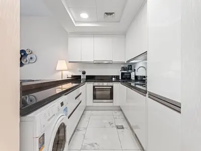 a kitchen with white cabinets and a washer and dryer at Cozy and Elegant 1 BDR In Noura Tower-37 in Dubai
