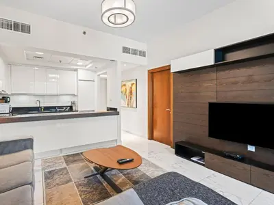 a living room with a couch and a tv and a table at Cozy and Elegant 1 BDR In Noura Tower-37 in Dubai