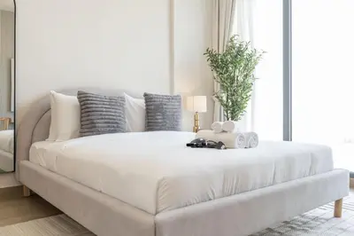 a white bed in a living room with a couch at StayShort - Spacious Studio in Town Square Sleeps 2 in Nadd Shubayḩ