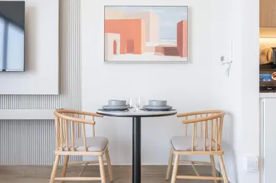 a dining room table with two chairs and a picture at StayShort - Spacious Studio in Town Square Sleeps 2 in Nadd Shubayḩ