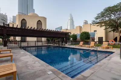 a large swimming pool with chairs and a building at Luxury Old Town Fountain View 2BHK front of Dubai Mall in Dubai