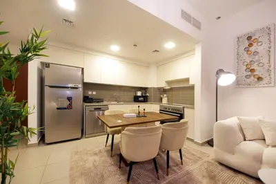 a kitchen with a wooden table and a refrigerator at Silk Valley - Green View Oasis: Stylish 2BR in Dubai’s Town Square in Dubai