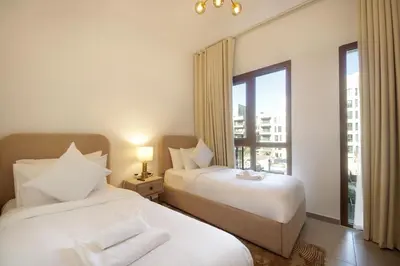 two beds in a hotel room with a window at Silk Valley - Green View Oasis: Stylish 2BR in Dubai’s Town Square in Dubai