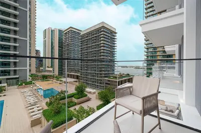 a chair on a balcony with a view of a city at Beachfront 2BR Marina & Beach Views in Dubai