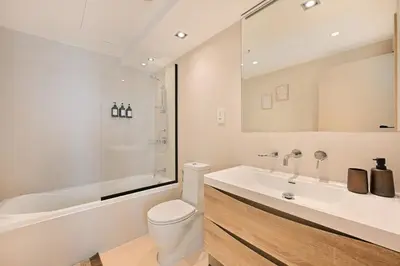a bathroom with a toilet and a tub and a sink at Curated High-Floor 2BR Sofa Bed Marina Water View in Dubai
