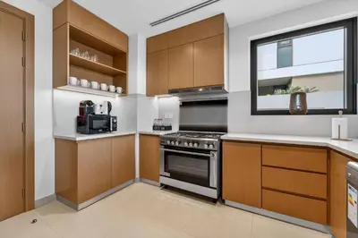 a kitchen with wooden cabinets and a stove at New, Bright & Modern 4BR Villa in Tilal Al Furjan in Dubai