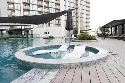 a swimming pool with two chairs and an umbrella at Stylish & Chic 1BR - The Crest at Sobha Hartland in Dubai