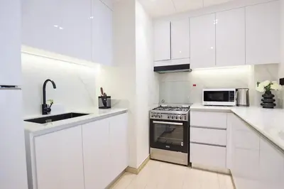 a white kitchen with a stove and a microwave at Prime 2BR in Binghatti Crest - JVC in Dubai