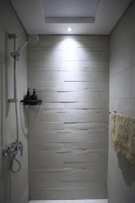 a bathroom with a shower with a tiled wall at Modern and cozy studio apartment in Dubai